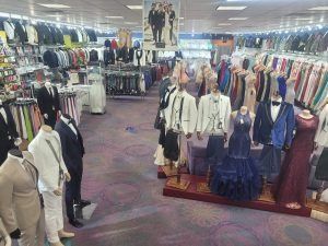 Clothing store aisle with men’s suits, jackets, and shirts displayed on mannequins and racks