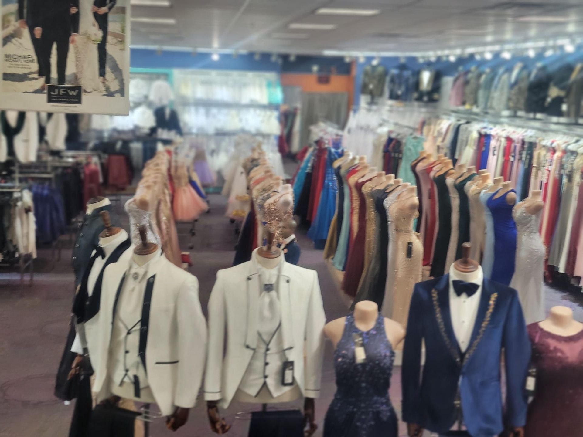 Clothing store interior with rows of formal suits and dresses on mannequins and racks