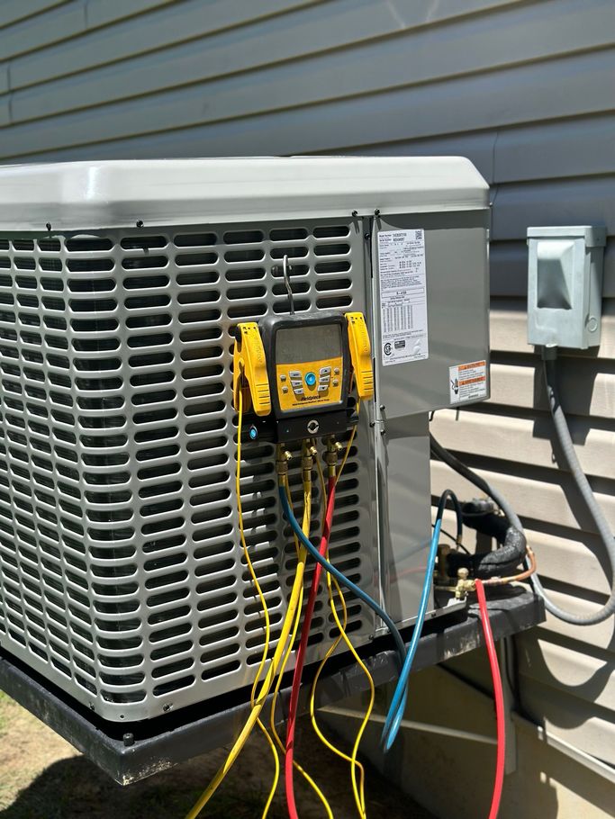 A Man in a Blue Hat is Working on an Air Conditioner — Holts Summit, MO — JC HVAC & Sons LLC