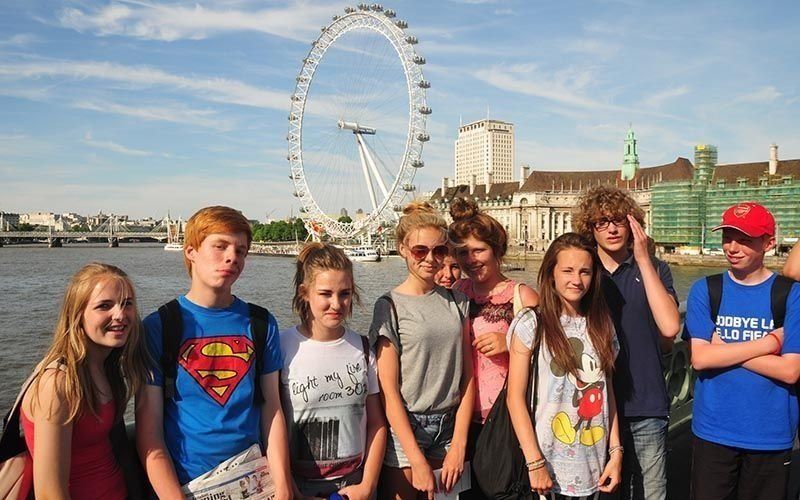 A group of young people standing in front of a ferris wheel