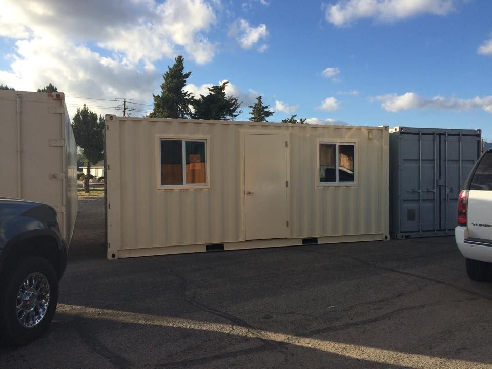 Two shipping containers are parked next to each other in a parking lot.