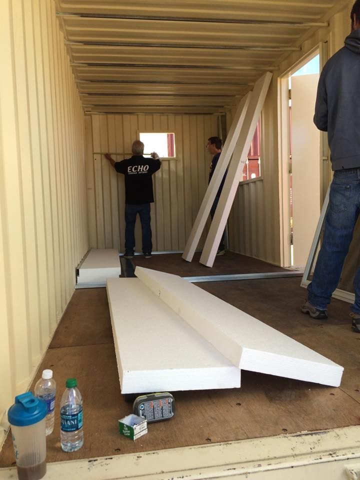 A man in a black shirt is standing in a shipping container.