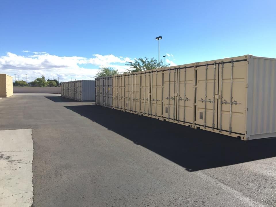 A row of shipping containers are lined up in a parking lot