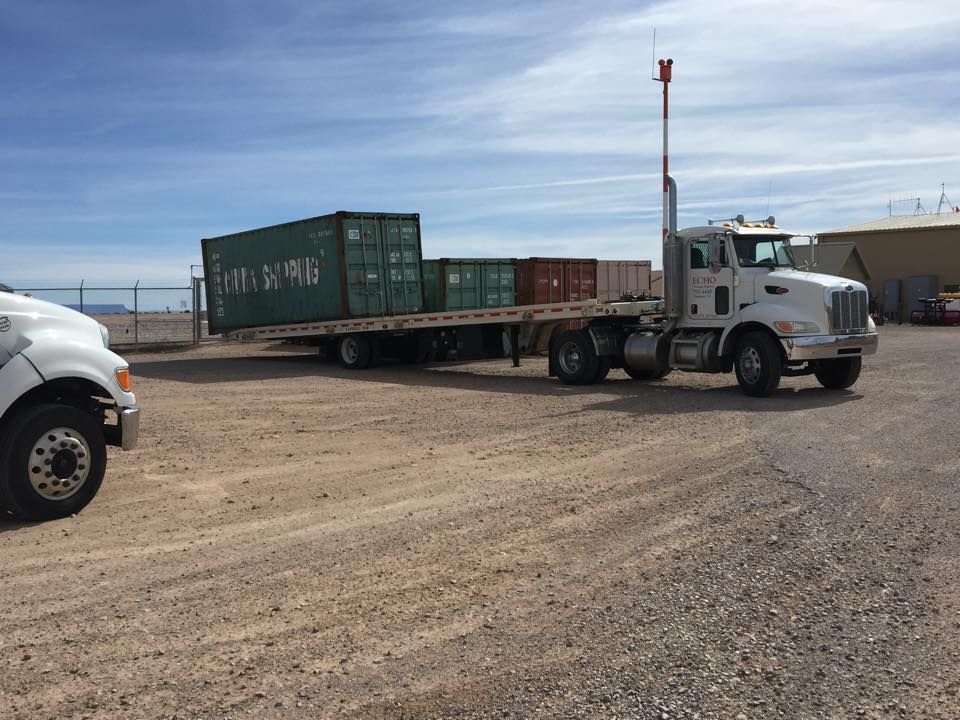 A semi truck is towing a trailer with containers on it.