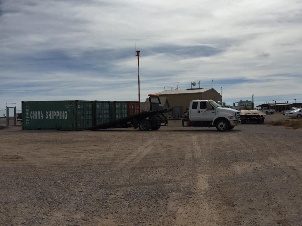 A white truck is towing a green shipping container