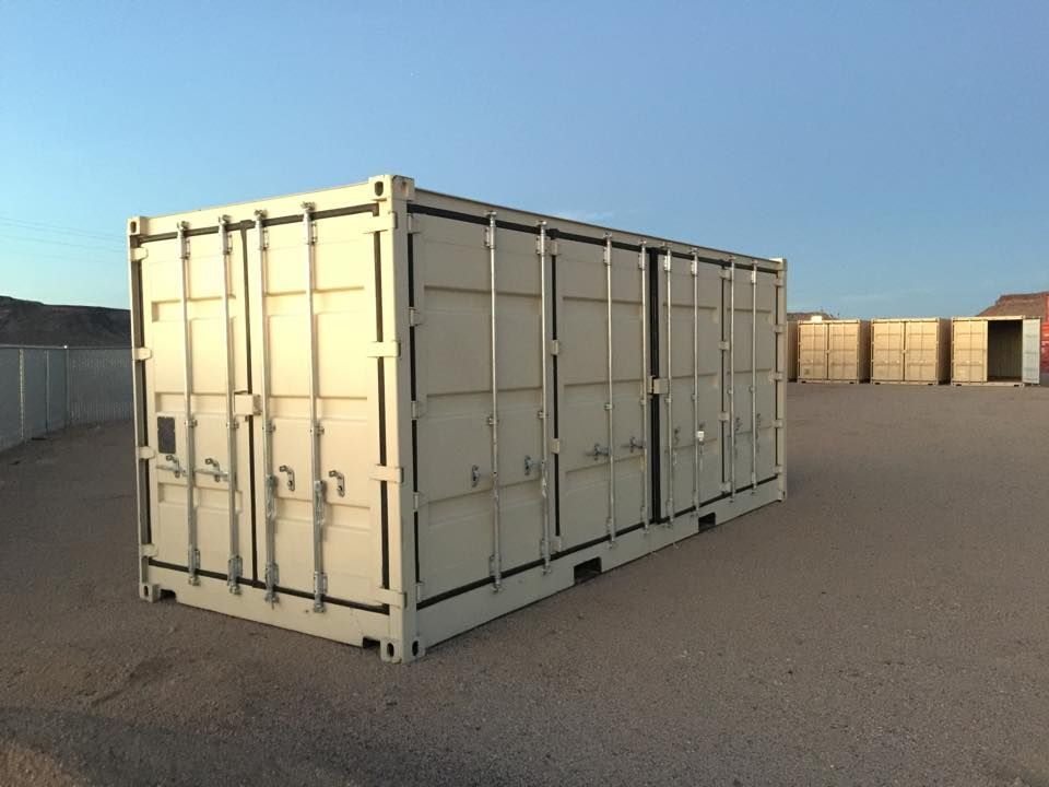A large shipping container is sitting in the middle of a dirt field