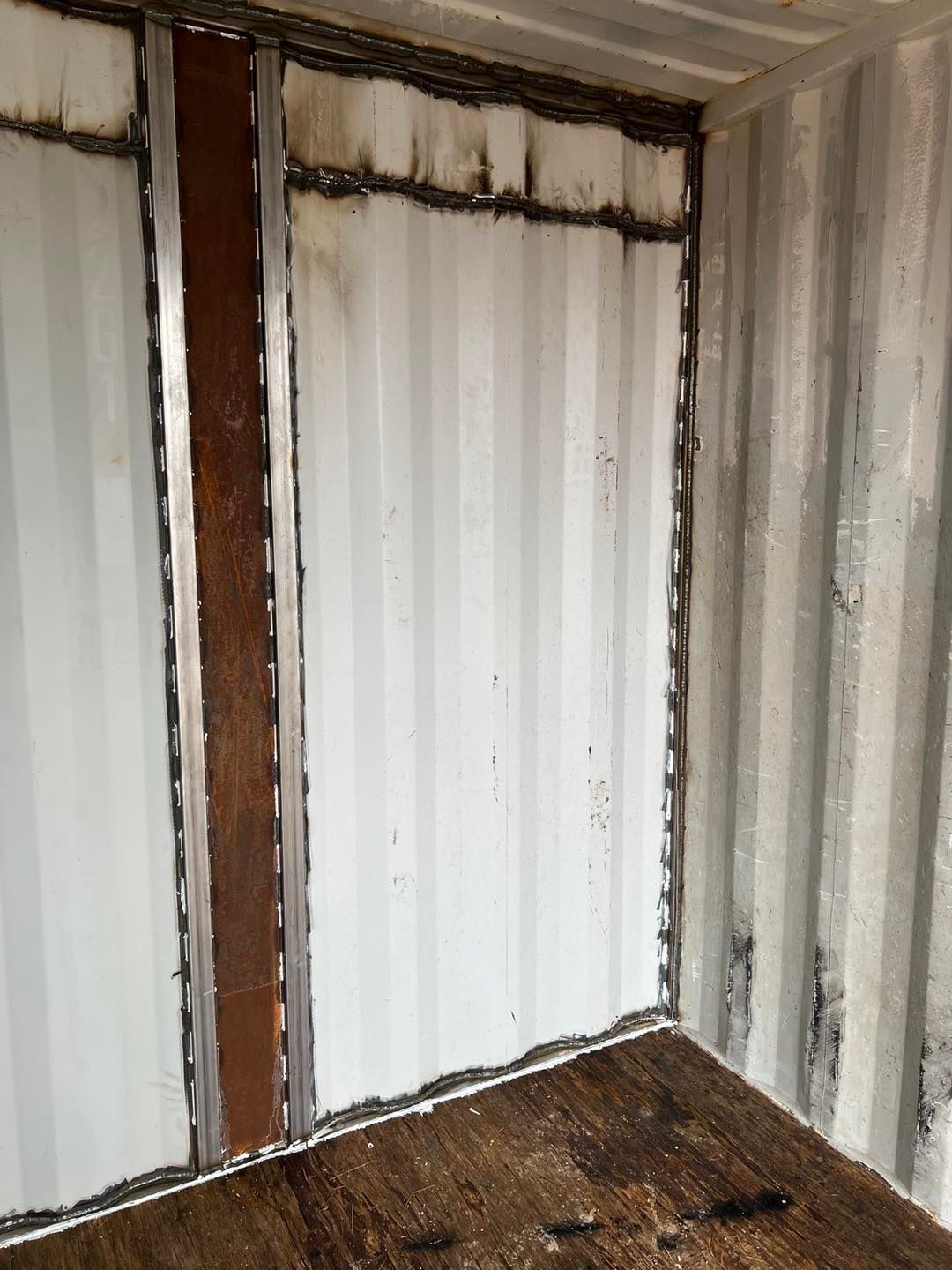 An empty room with a wooden floor and a white wall.