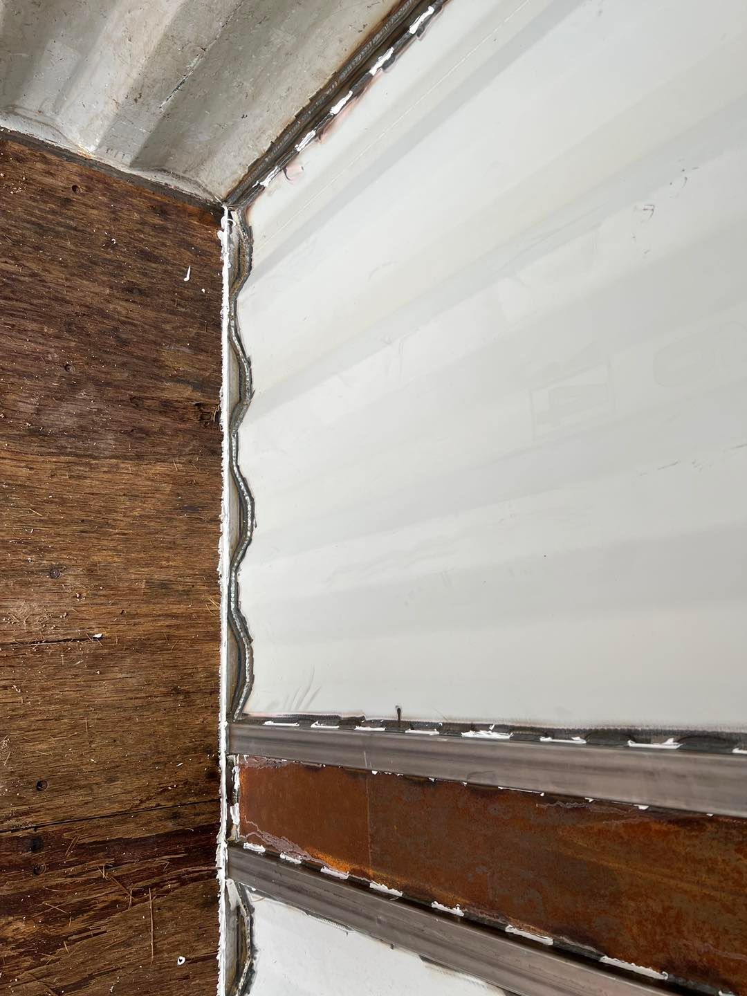 A close up of a garage door with a wooden wall behind it.