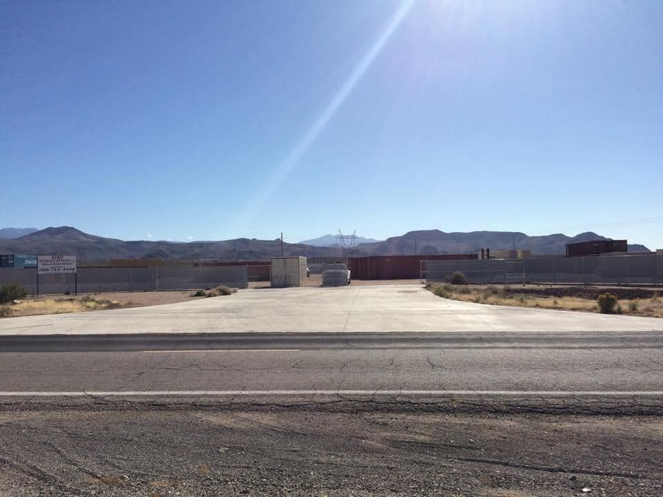 A concrete driveway leading to a large building with mountains in the background.
