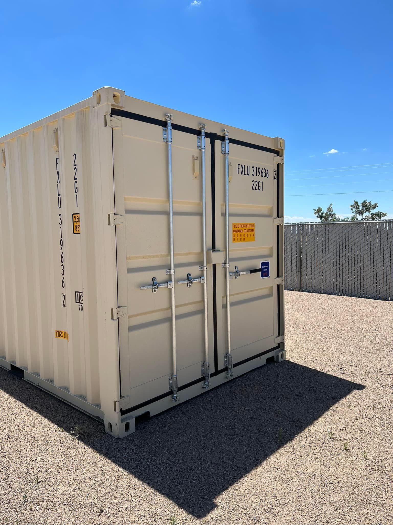 A shipping container is sitting on top of a gravel lot.