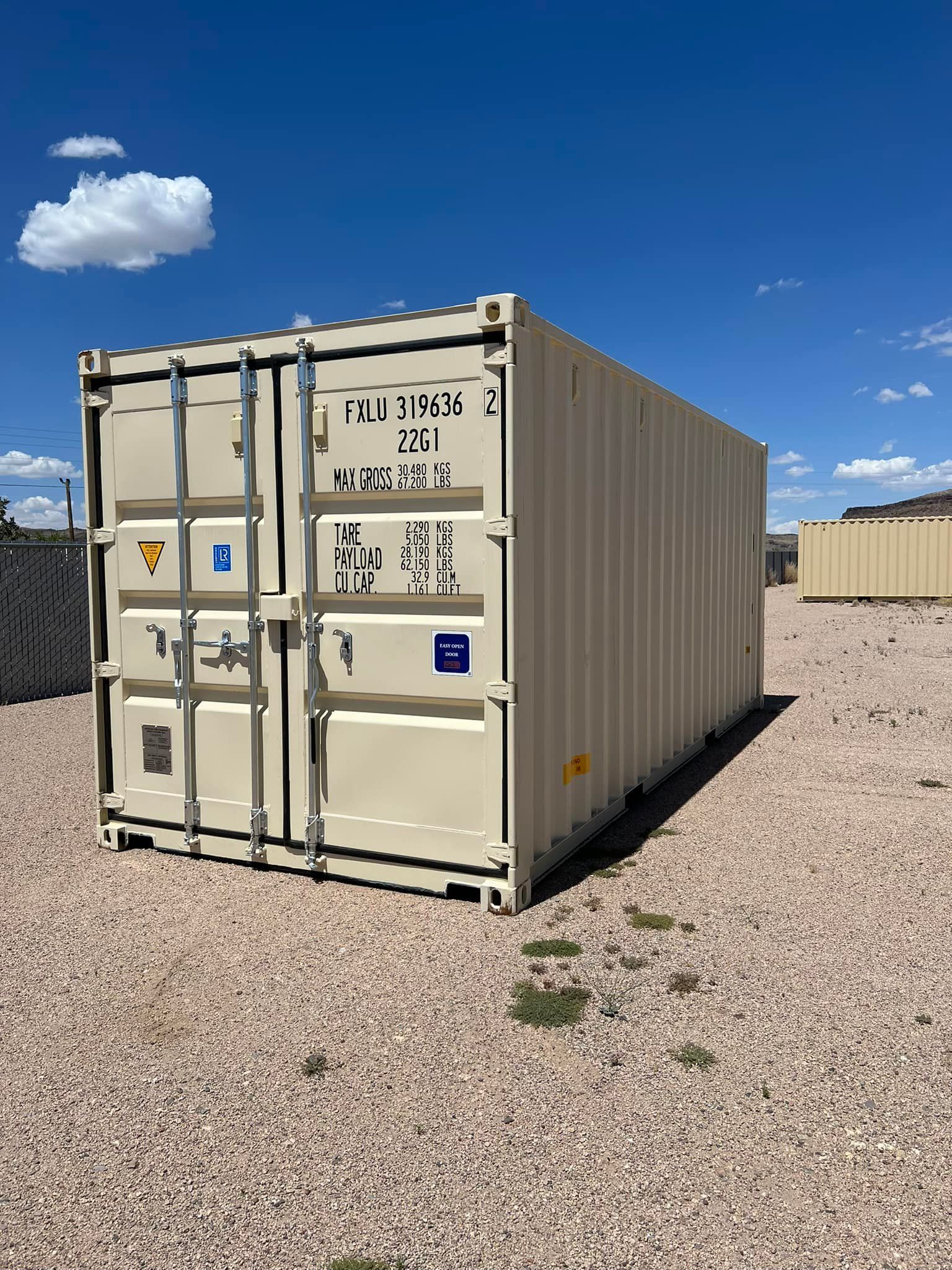 A shipping container is sitting on top of a gravel field.