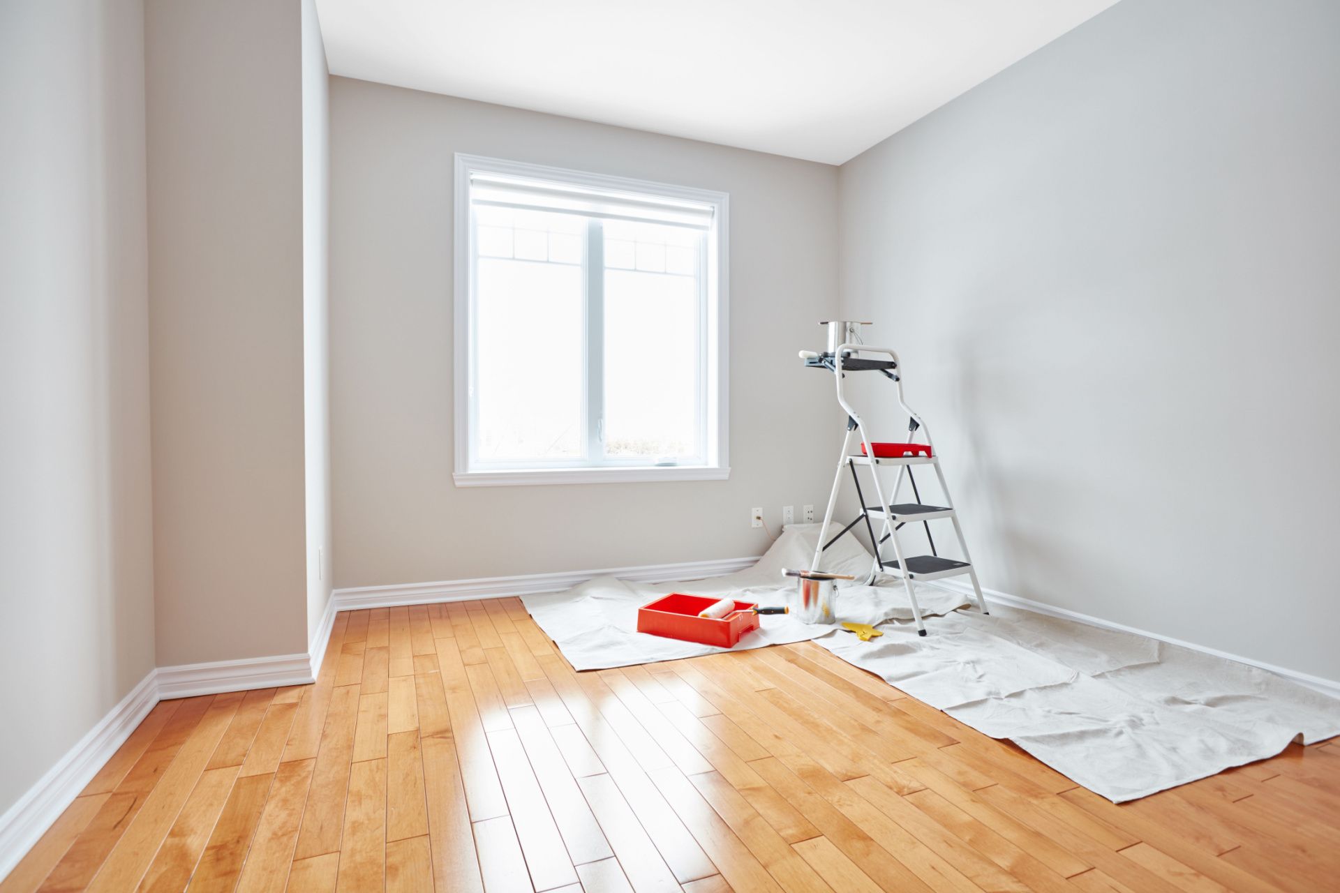 an empty room with hardwood floors and a ladder .