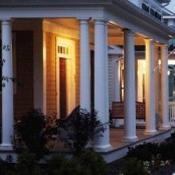 A porch of a house with white columns and a bench.
