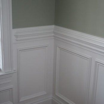 A corner of a room with white wainscoting and a window.
