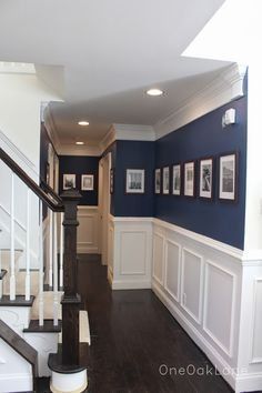 A hallway with blue walls and white trim and stairs