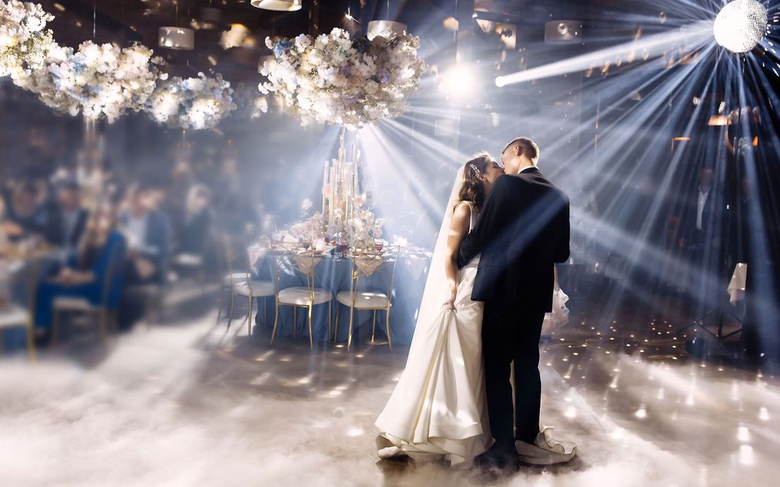 A bride and groom are dancing their first dance at their wedding reception.