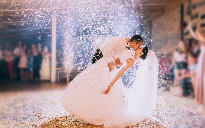 A bride and groom are kissing during their first dance at their wedding reception.