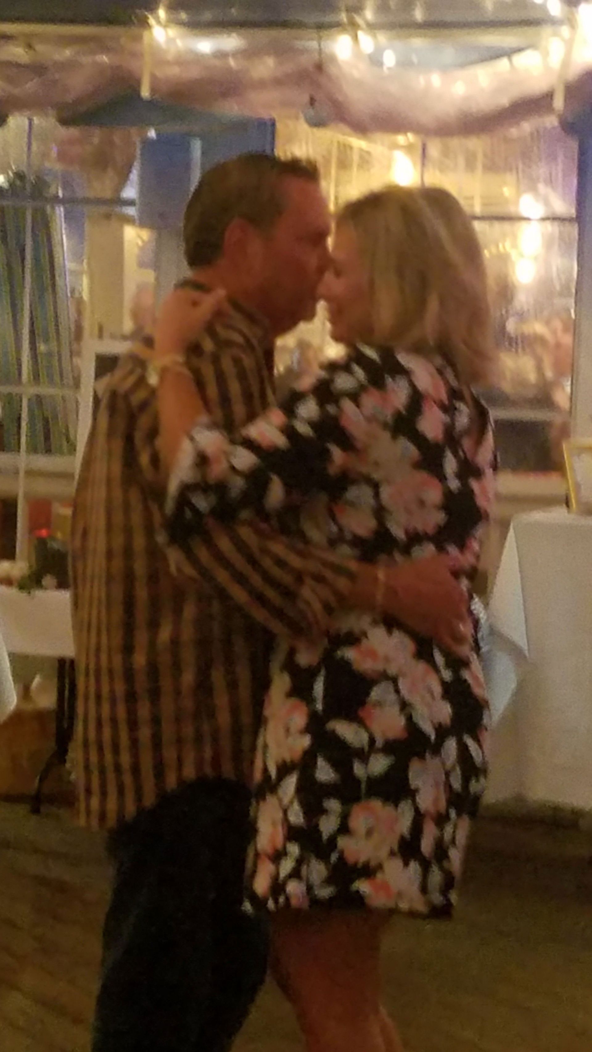 A man and a woman are kissing while dancing in a room.