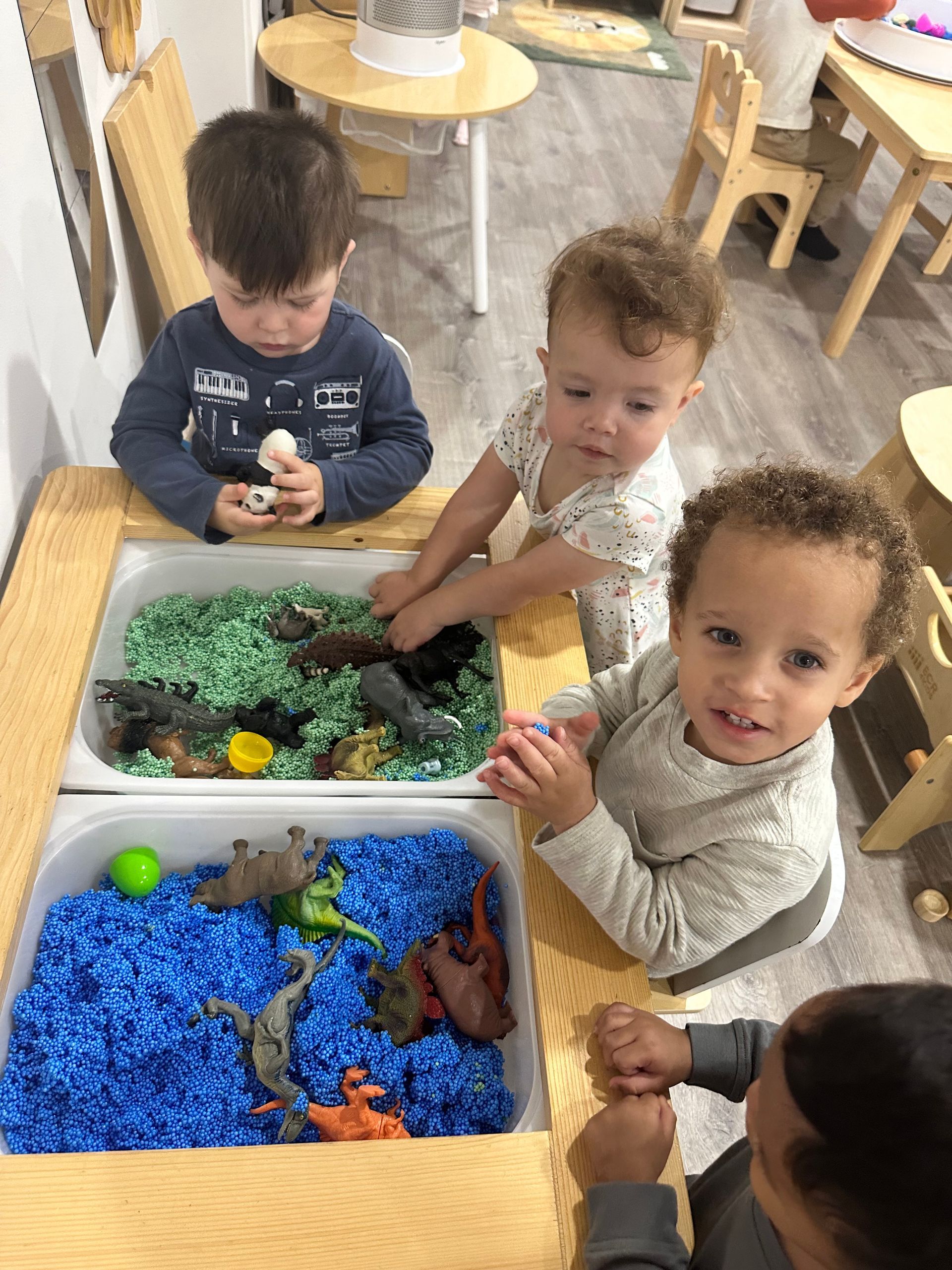 Child playing with colorful number puzzle, smiling. Indoors, wooden table.