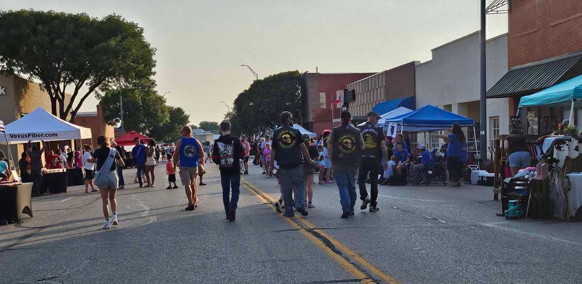 People walking down a street lined with vendor tents and buildings.