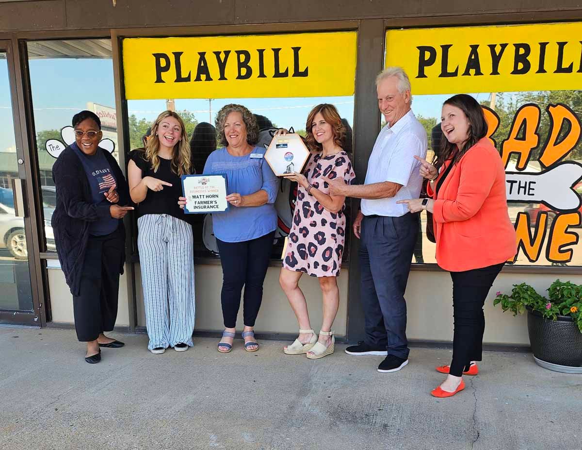 People holding plaque and key outside a building with 