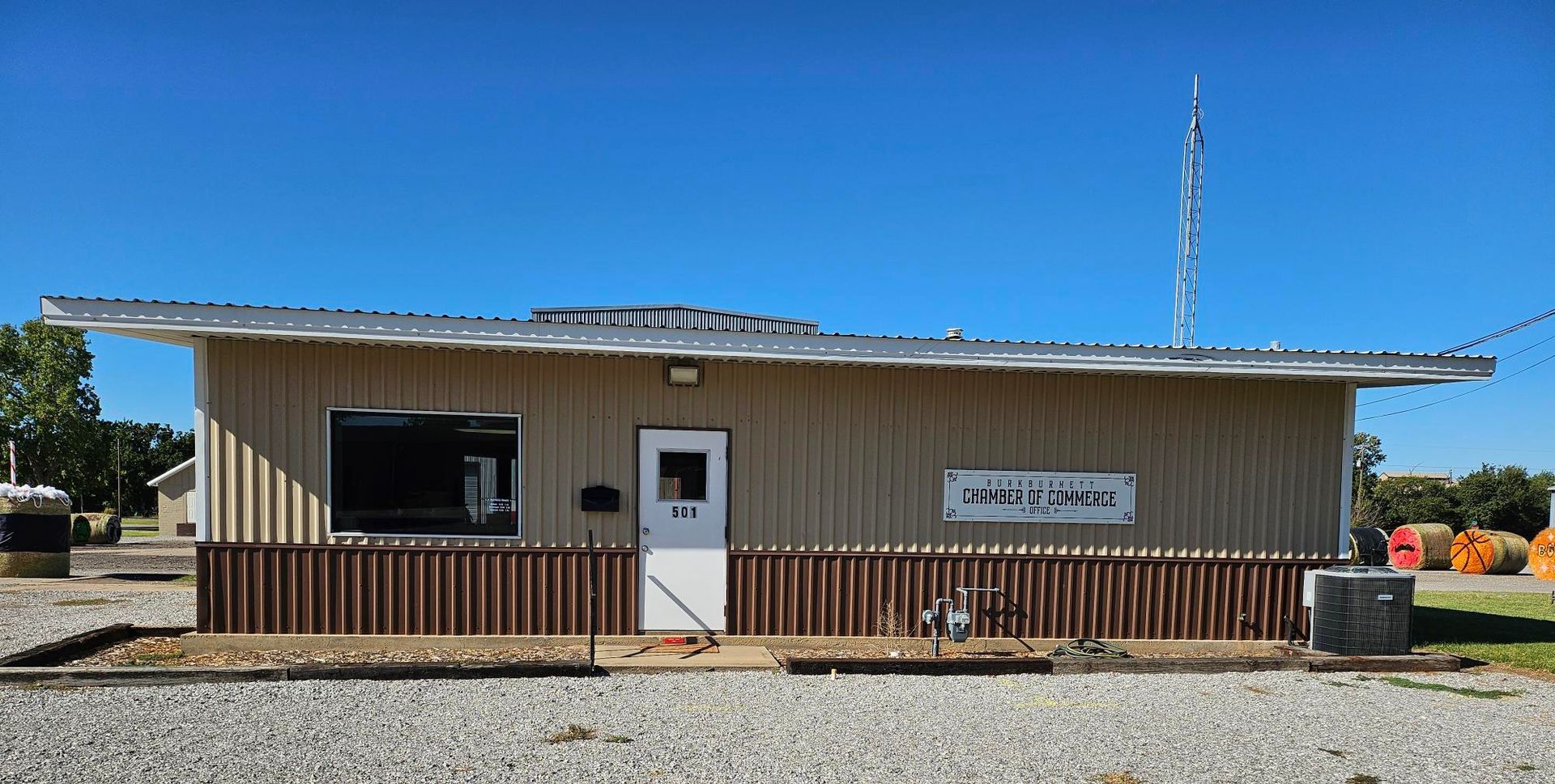 A tan, single-story building with a metal roof and a sign that reads 