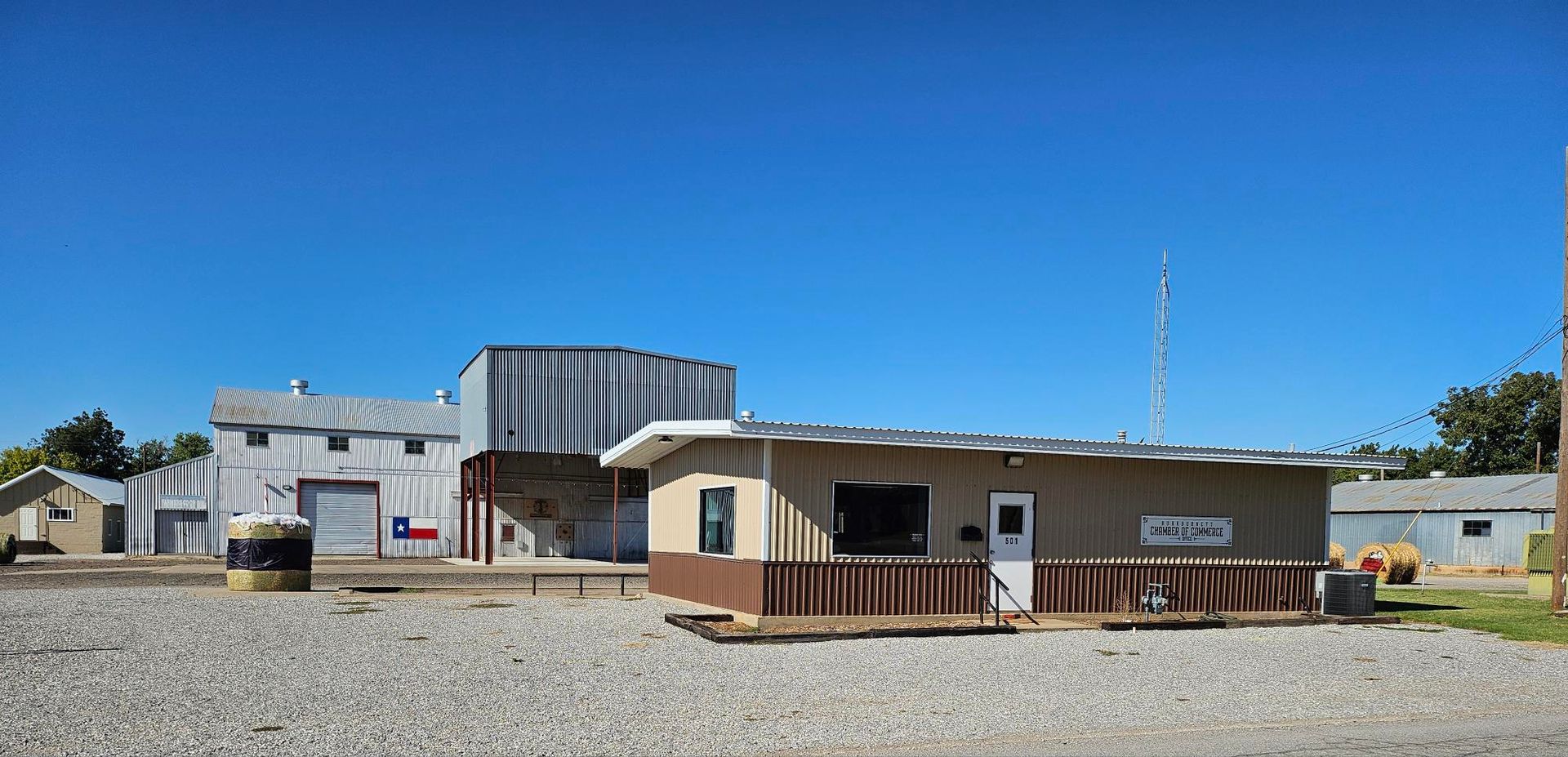 A small town scene with several metal buildings under a clear blue sky.