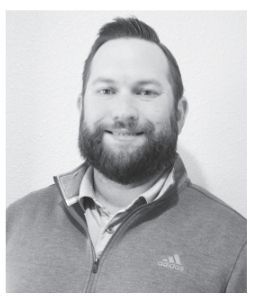Man with beard, smiling, wearing a gray zip-up jacket over a collared shirt.