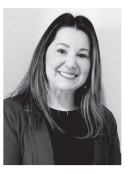 Woman smiling, wearing a dark top and cardigan, looking at the camera.