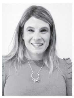 Woman with long hair smiles, wearing a grey shirt and necklace.