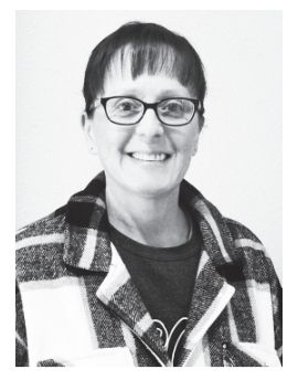 Woman wearing glasses, smiling, with short hair, plaid jacket.