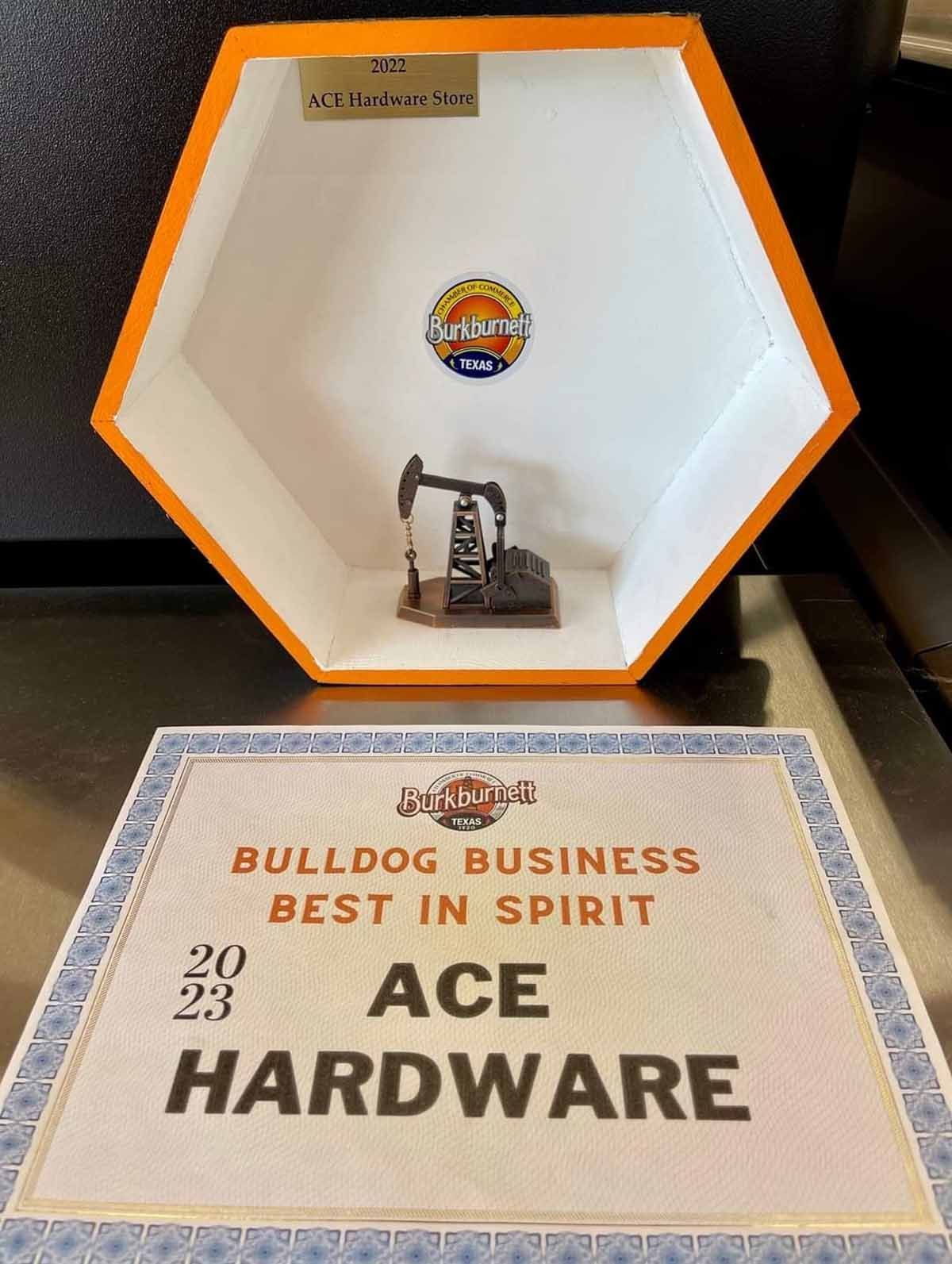 Trophy in orange hexagonal case with a miniature oil rig; below is an award that says 