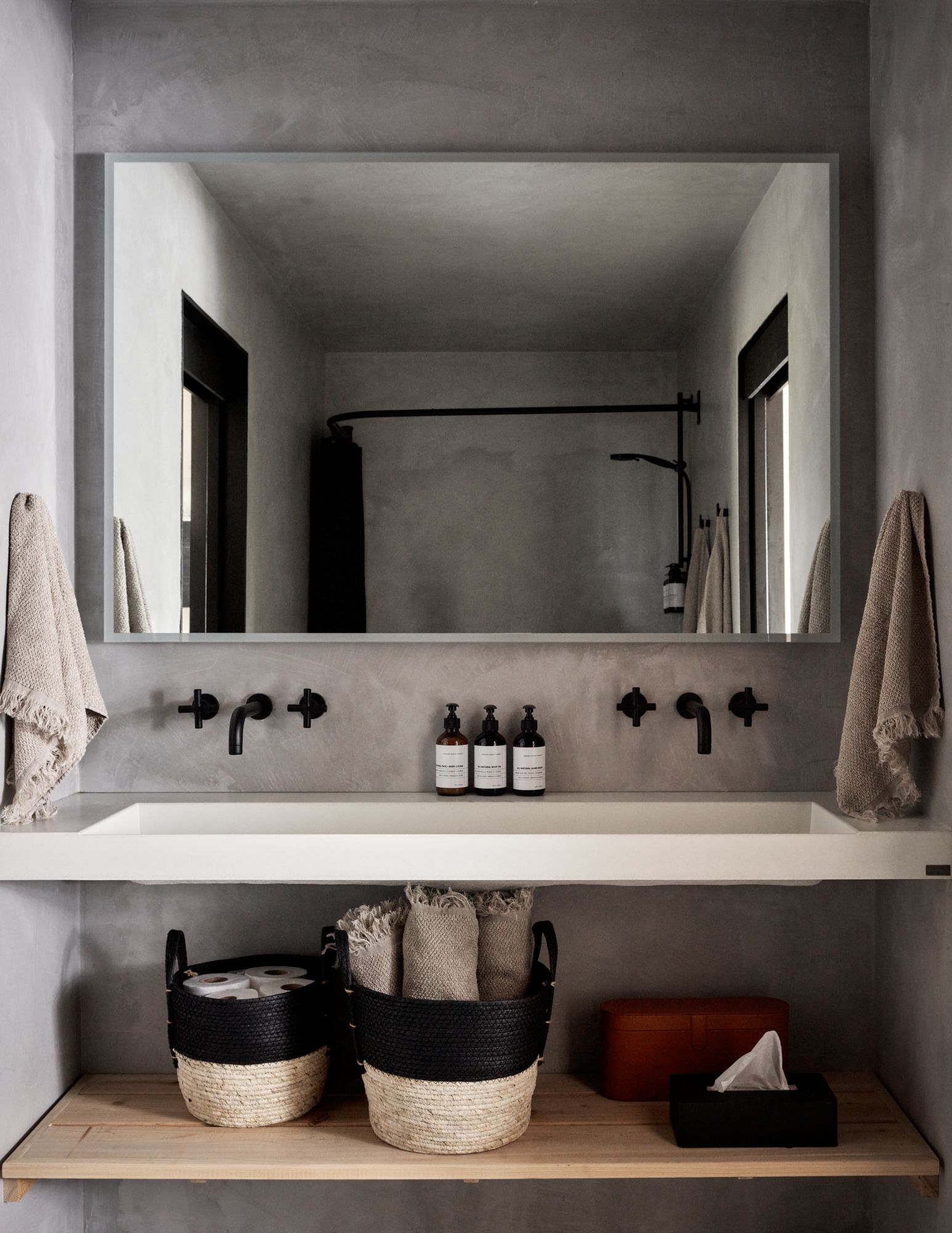 Modern bathroom with a large mirror over a double sink, black fixtures, and gray walls.