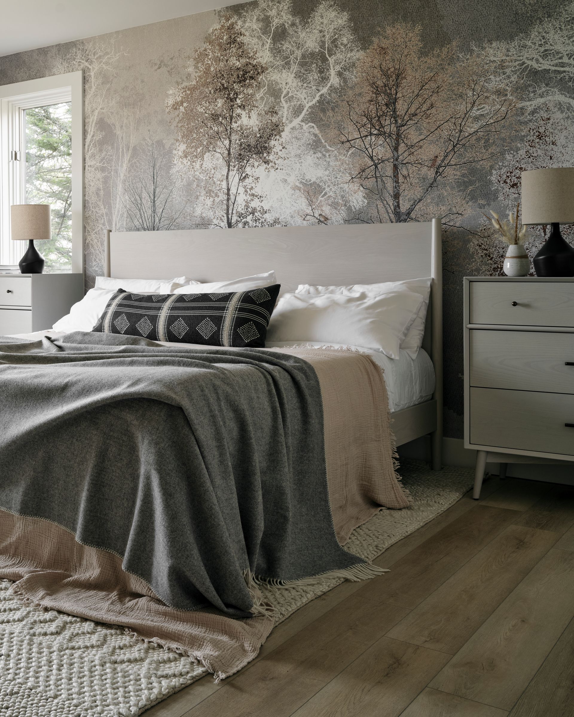 Bedroom with gray bed, nightstands, and woodland mural wallpaper.