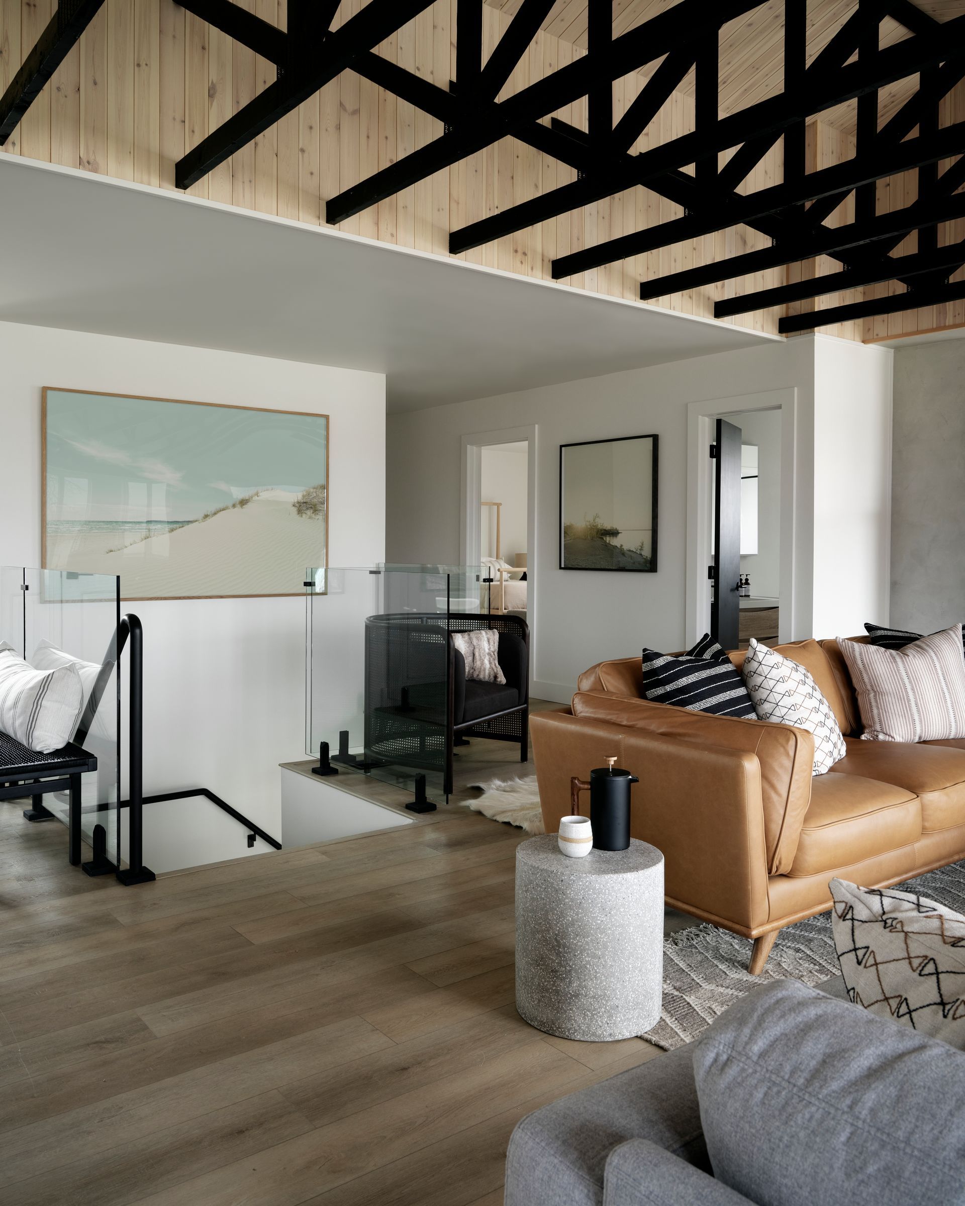 Living room with leather sofa, art, and black beams.