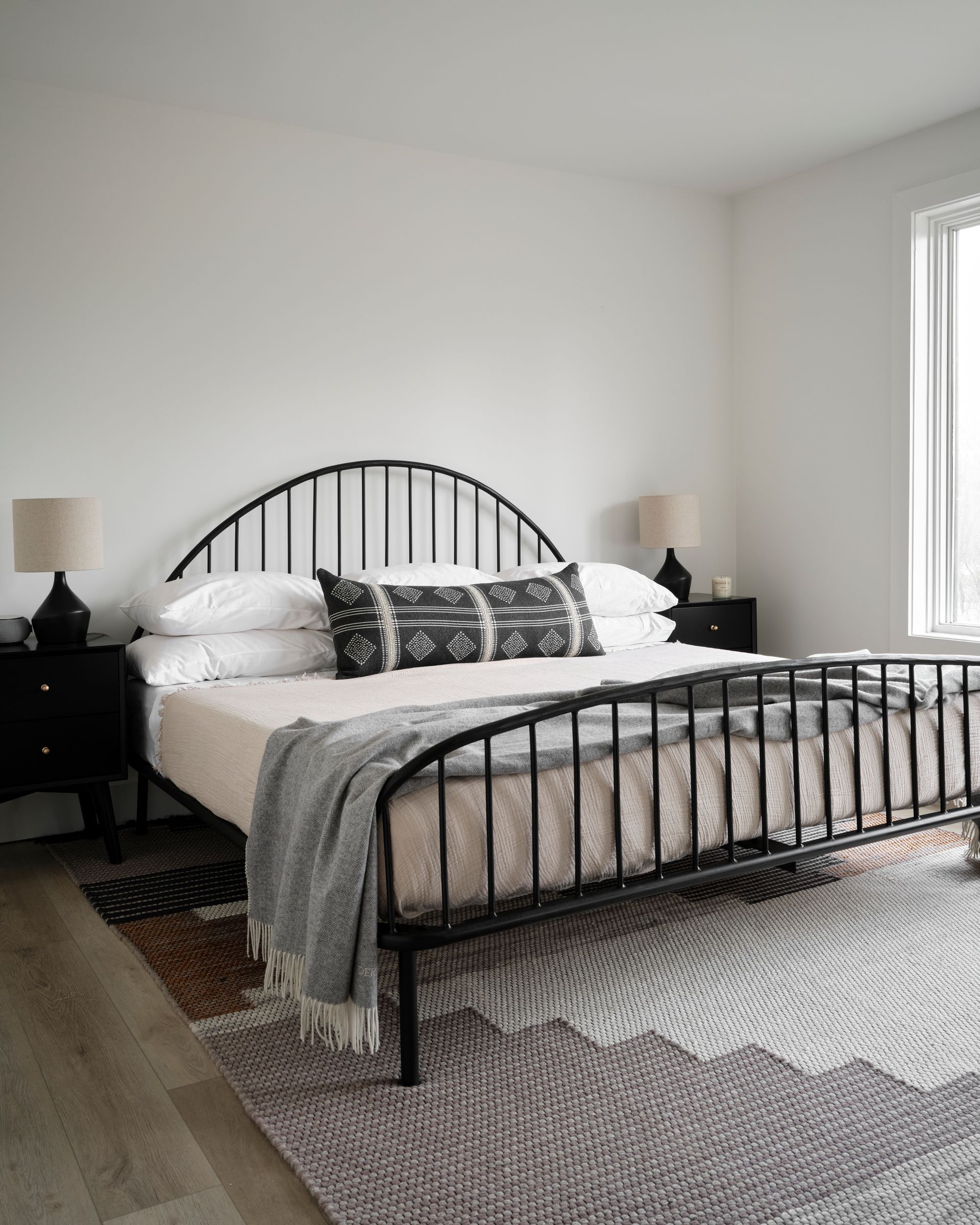 Bedroom with black metal bed, bedside tables, and patterned rug.