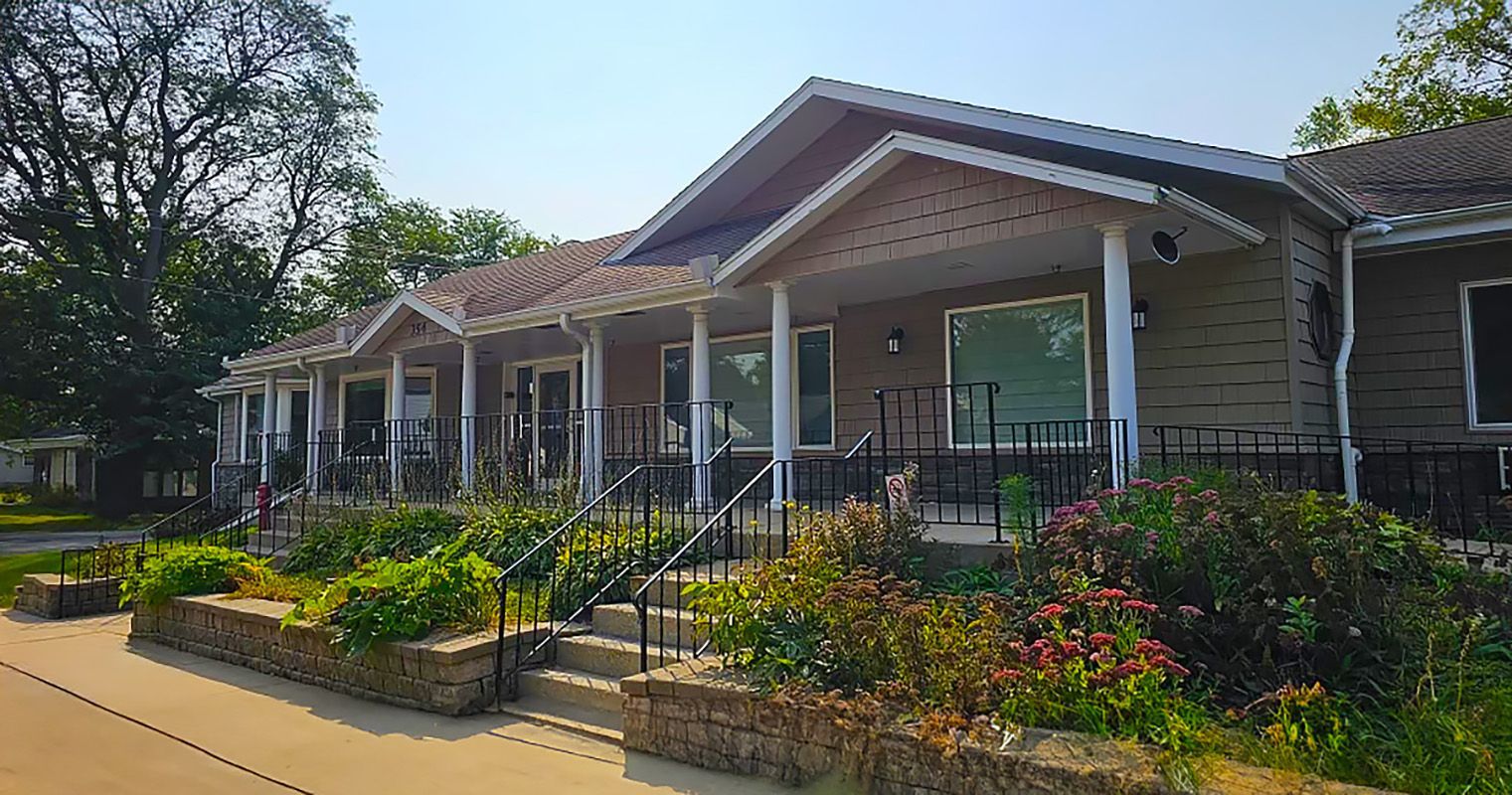 A large house with a large porch and a lot of flowers in front of it.