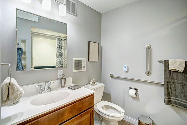 A bathroom with a toilet , sink and mirror.