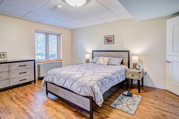 A bedroom with a bed , dresser , nightstand and window.