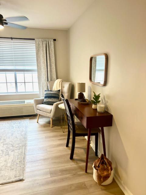A living room with a desk , chair , and mirror.