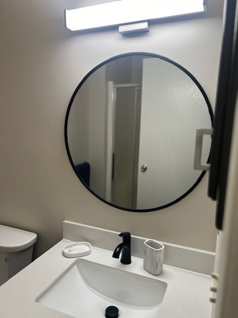 A bathroom sink with a round mirror above it