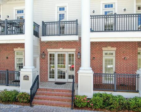 A multi-story brick building with white columns, balconies, glass-paned doors, and a front staircase.
