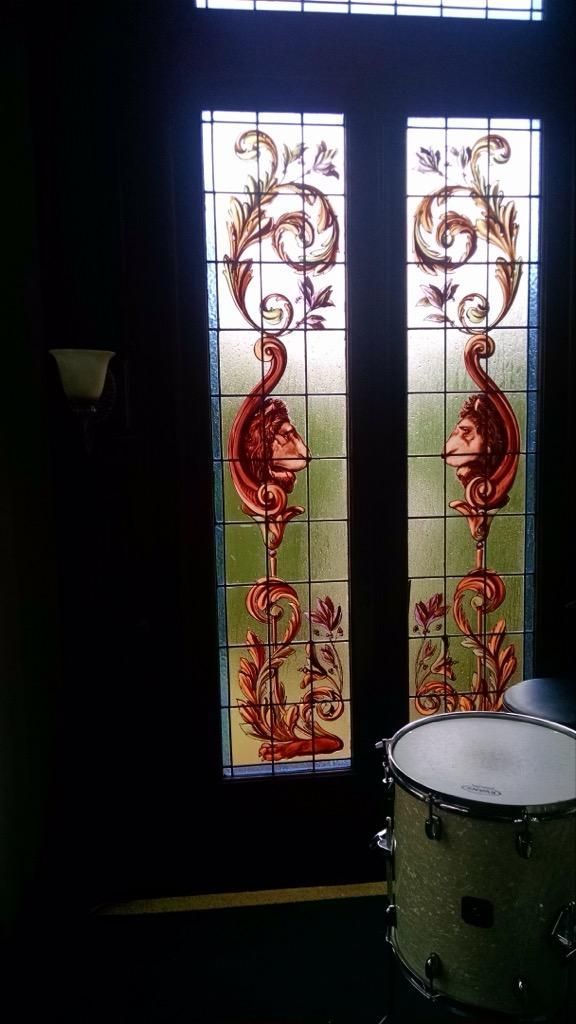 A drum is sitting in front of a stained glass window.