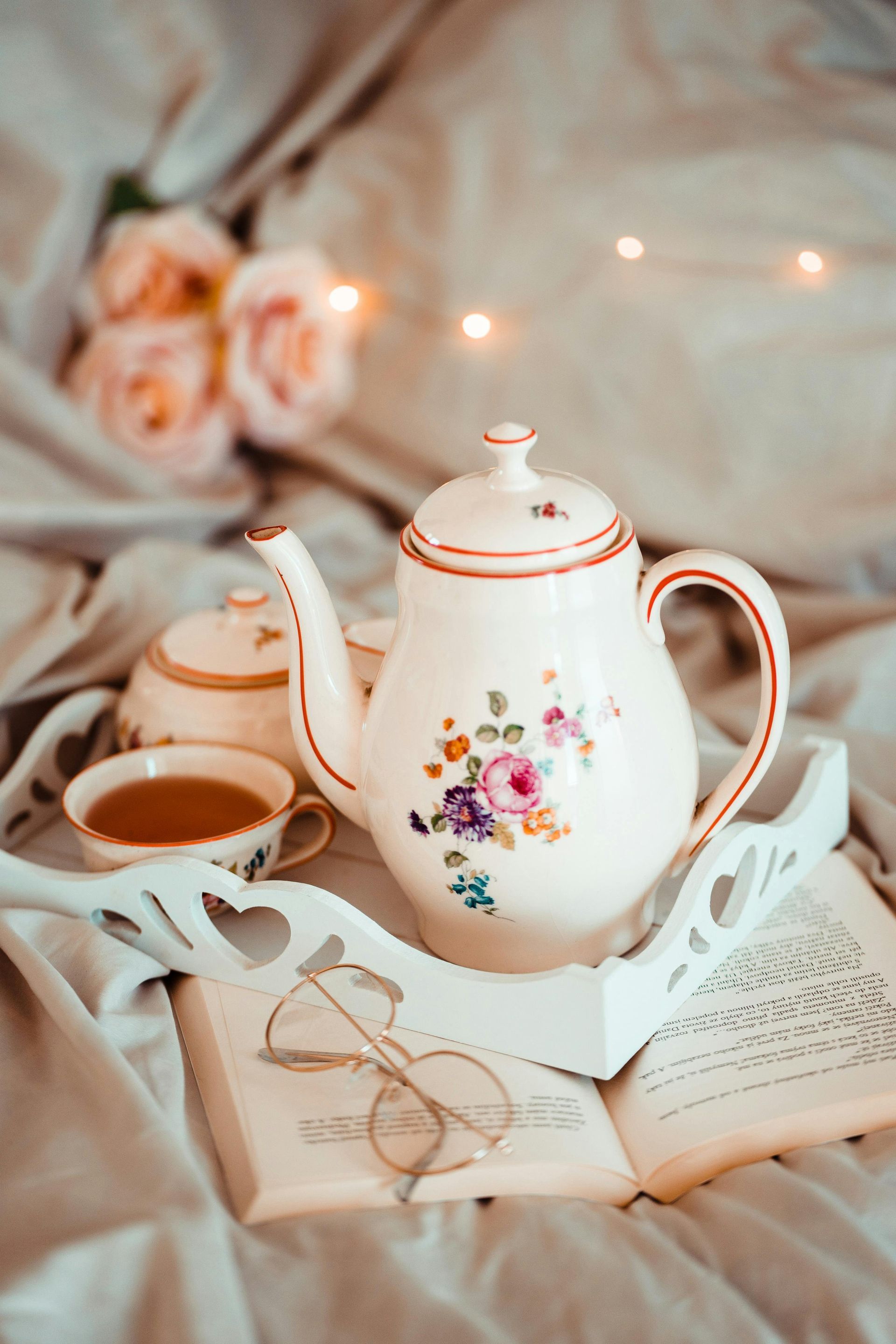 A teapot and cup of tea are on a tray on top of an open book.