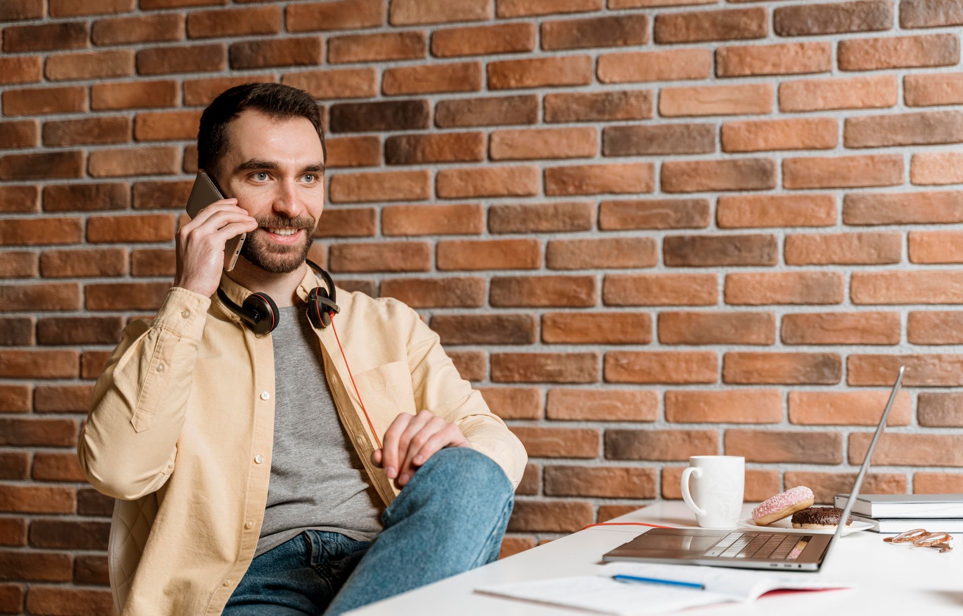 A man is sitting at a table talking on a cell phone.