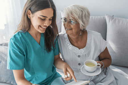 Companionship — An Old Woman Holding a Cup of Coffee Beside the Nurse in Lincoln, NE