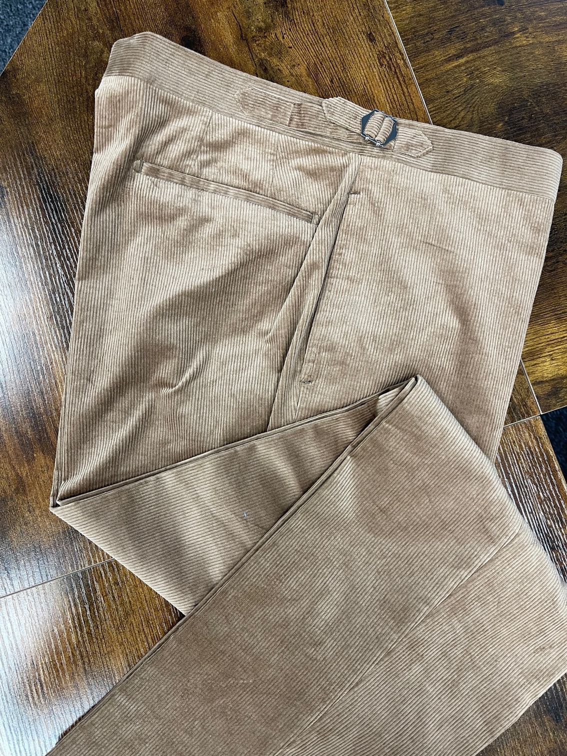 A pair of brown pants are sitting on top of a wooden table.