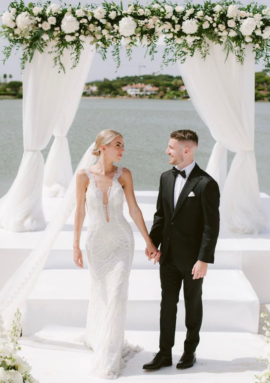 A bride and groom are holding hands during their wedding ceremony.