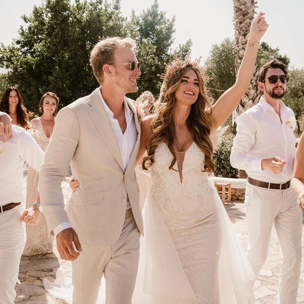 A bride and groom are walking with their wedding party.