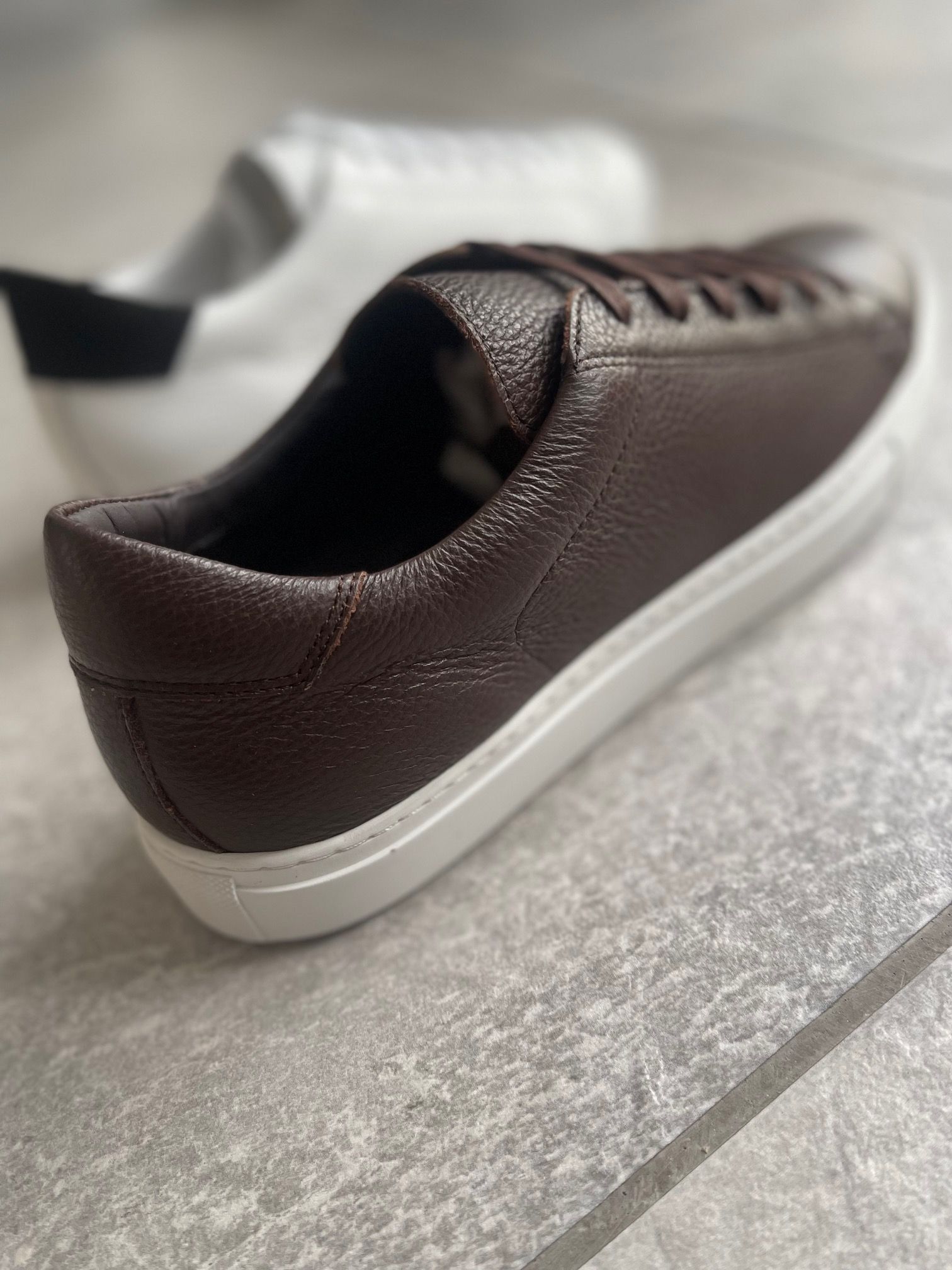 A pair of brown and white sneakers are sitting on a tiled floor.